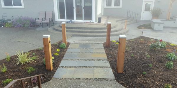 New stone pathway with wooden posts in a garden.