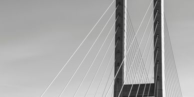 Black and white image of a cable-stayed bridge tower with suspension cables.