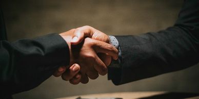 Two people shaking hands over a table.