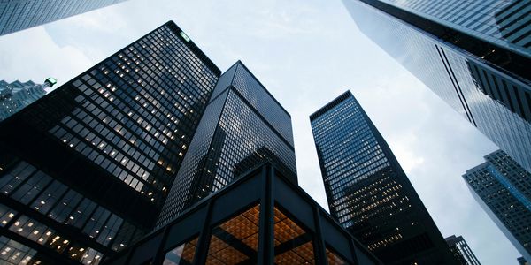 Looking up at towering glass skyscrapers in a cityscape.
