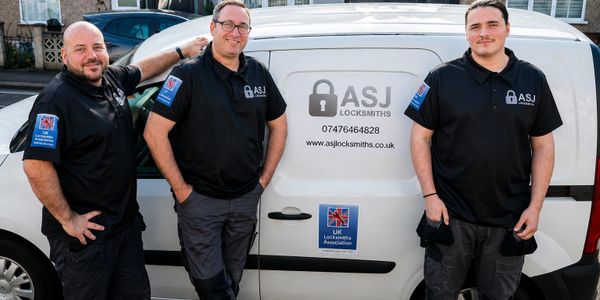 Three locksmiths in uniform pose confidently by their branded service van.