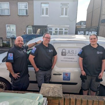 Three security professionals posing by a white ASJ Locksmiths van.