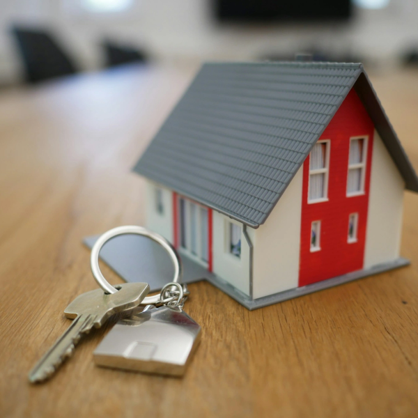 Model house with keys on wooden table.