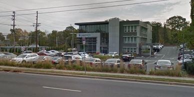 Modern office building with a parking lot full of cars on a cloudy day.
