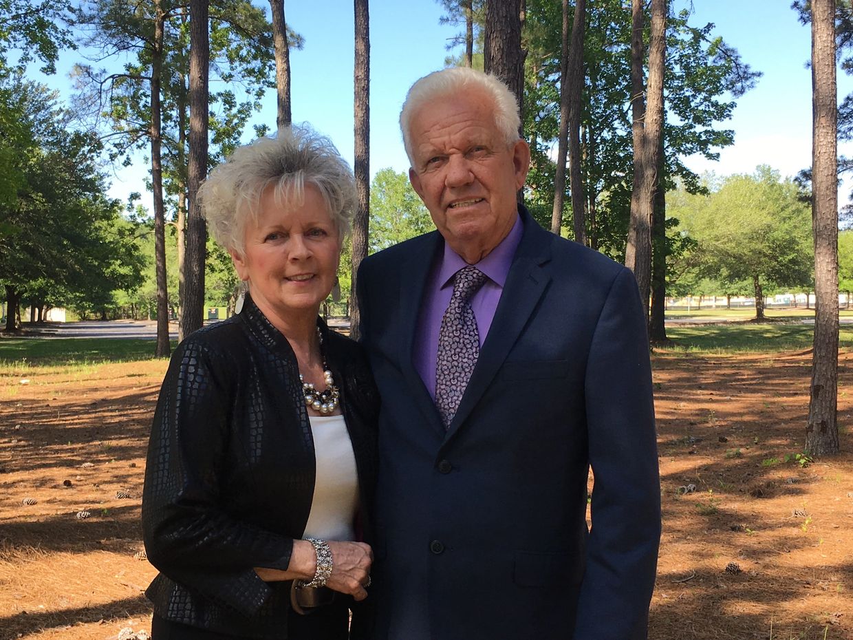 An elderly couple posing outdoors.