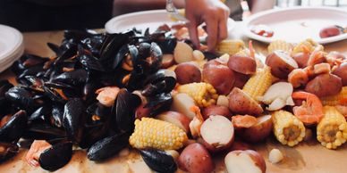 A seafood boil with mussels, shrimp, corn, and potatoes on a table.