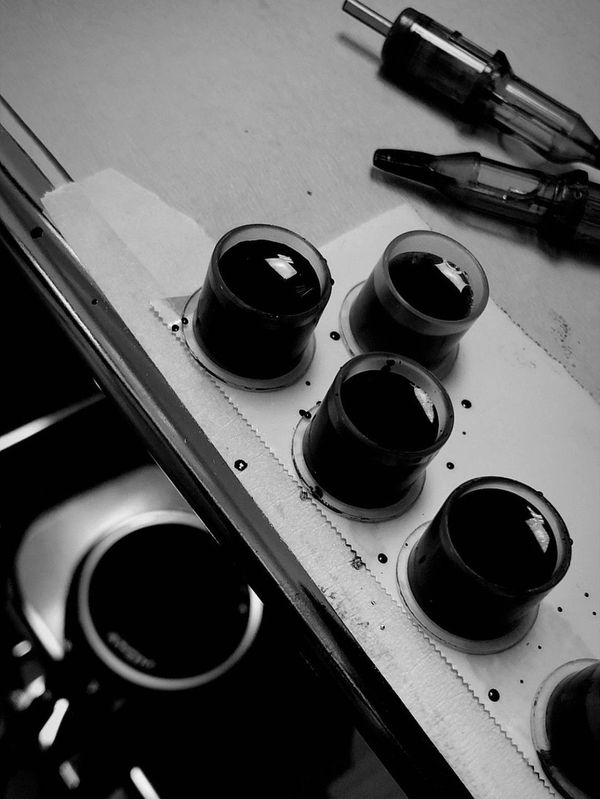 Black ink caps and tattoo machine needles on a workstation.