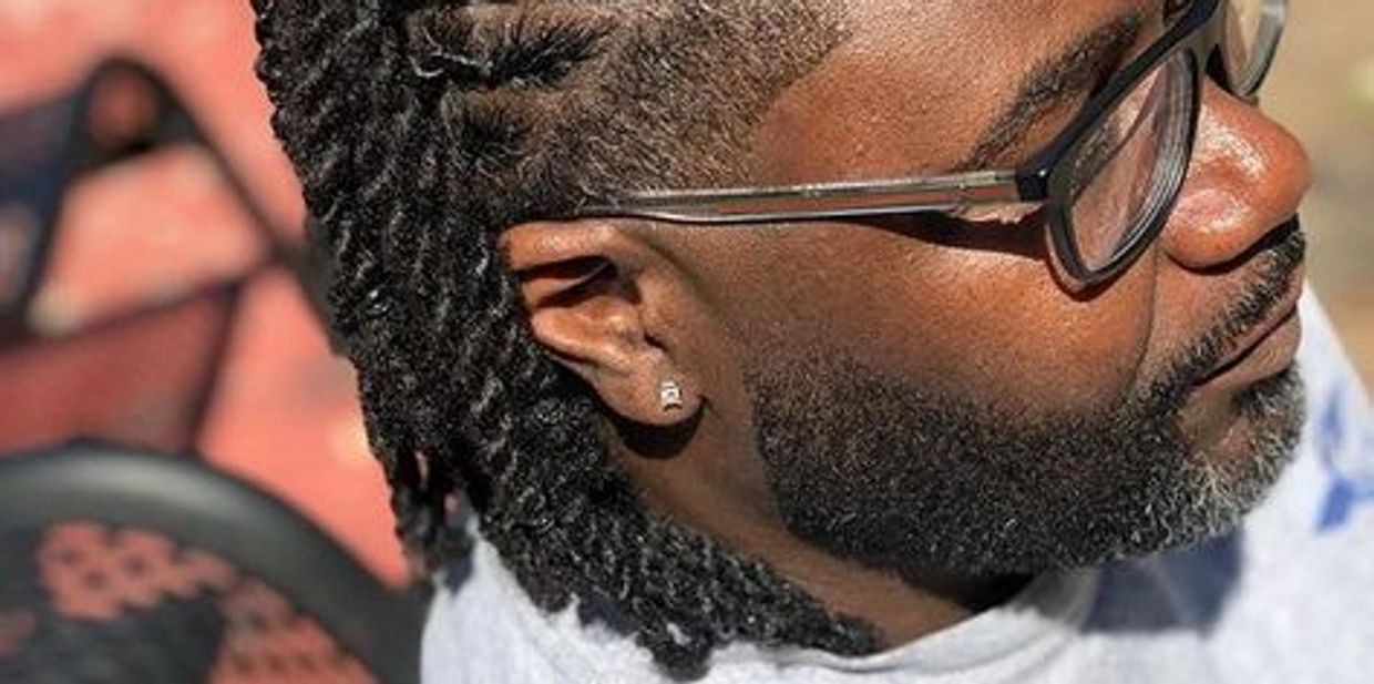 Side profile of a man with glasses and twisted hair.