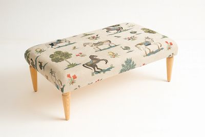 Upholstered bench with horse and floral print and wooden legs.