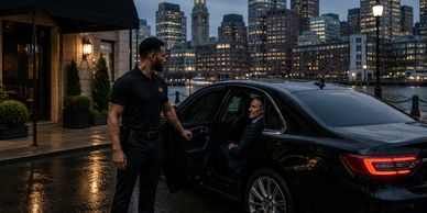 A chauffeur opens a car door for a passenger in a city at night.