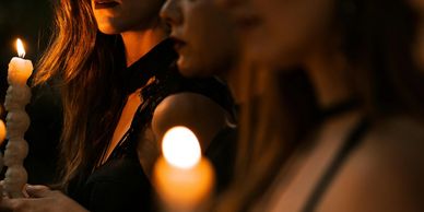 Three women in dim light holding candles.