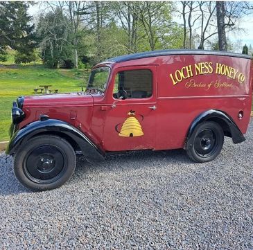 Vintage red delivery van for Loch Ness Honey Co., featuring a bee and hive logo.