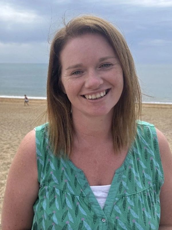 Smiling woman at the beach on a cloudy day.