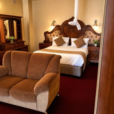 Cozy bedroom with brown sofa and ornate wooden bed.