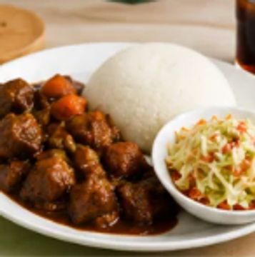 Plate of stew, rice, and coleslaw with a drink.