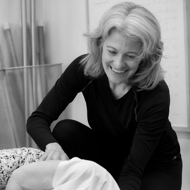 Woman smiling while assisting someone in a therapeutic session.