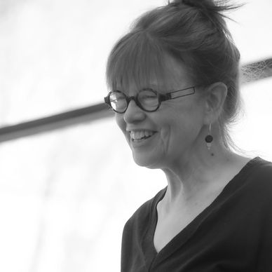 Smiling woman with glasses in black and white portrait.
