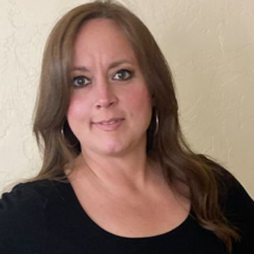 A woman with long brown hair wearing a black top and hoop earrings.