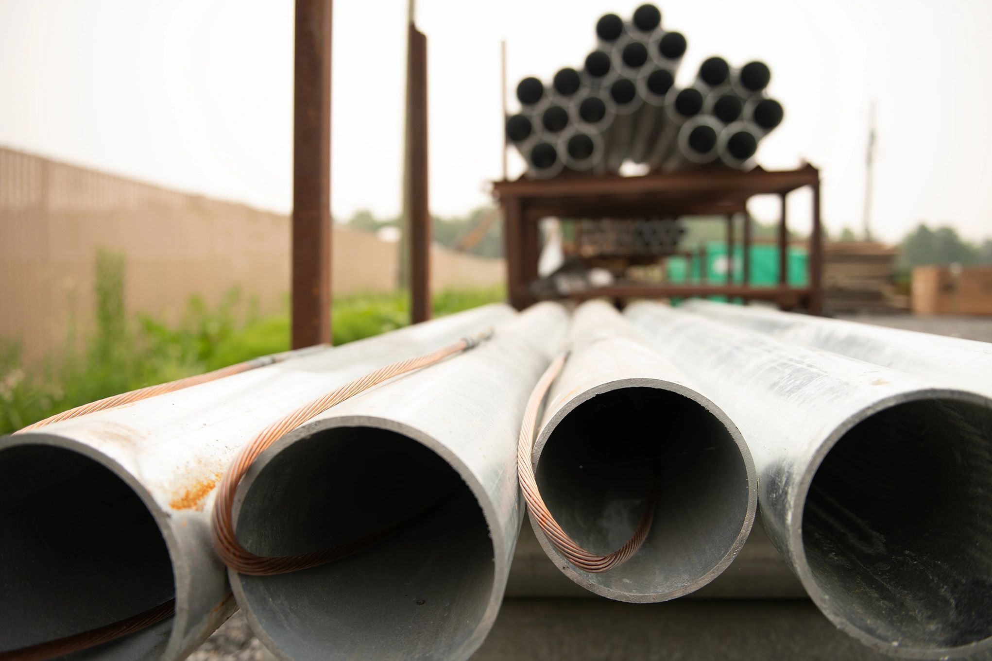 Stacked metal pipes with copper wire on a construction site.