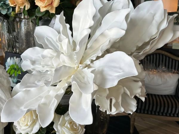 Large white flower with ruffled petals in an elegant indoor setting.