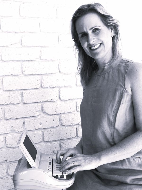 A black-and-white photo of Bernadette McGoldrick, smiling as she types on a stenography machine.