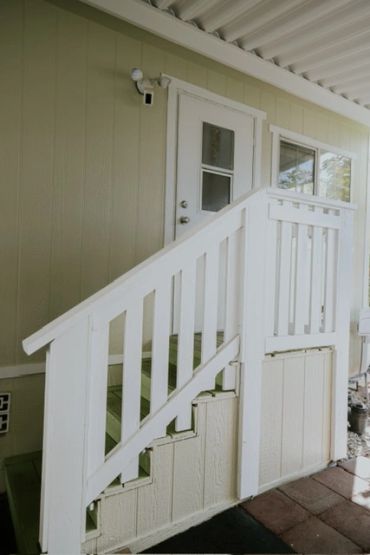 White wooden staircase leading to a door under a covered porch.
