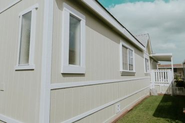 Exterior side view of a beige house with white trim and windows.