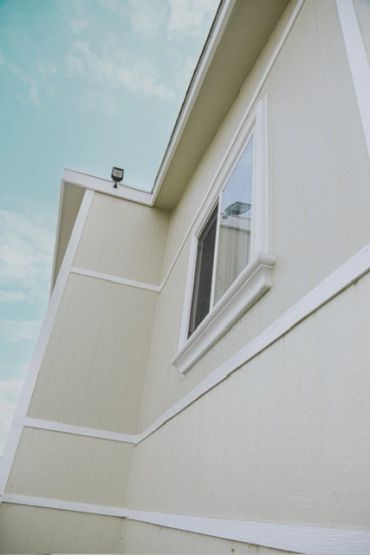 Close-up of a beige house exterior with a window under a blue sky.