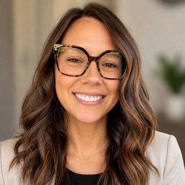 Smiling woman with wavy brown hair and stylish glasses.