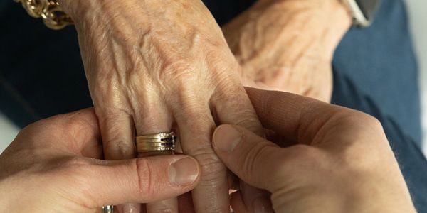 Hands exchanging a ring, symbolizing commitment or support.