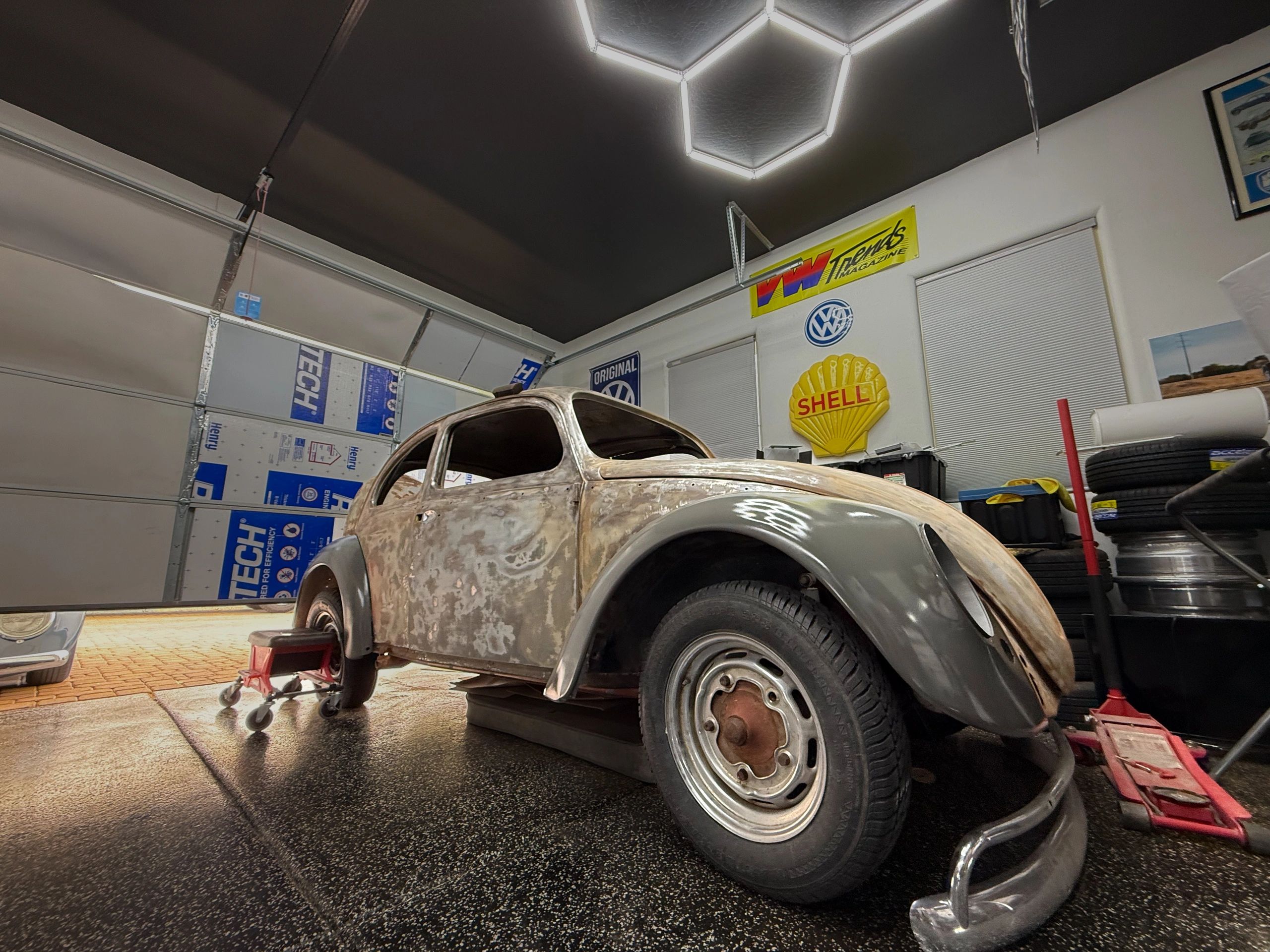 Rusty vintage car in a garage undergoing restoration.