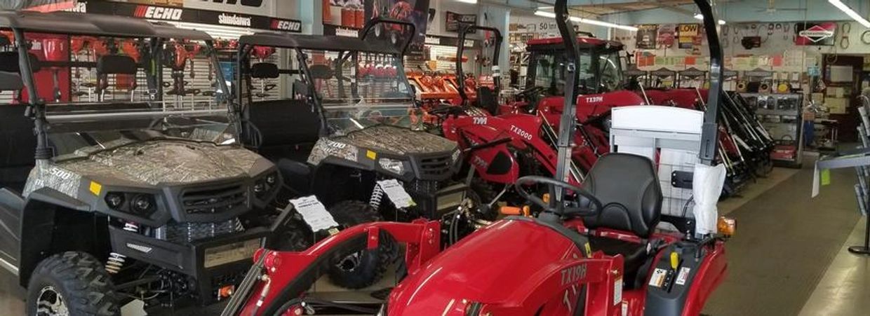 Red tractors and UTVs in a showroom.