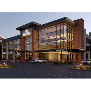 Modern three-story medical building with large glass windows and parked cars at dusk.