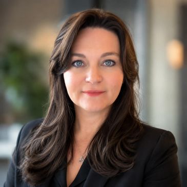 Professional woman with long dark hair in black jacket.