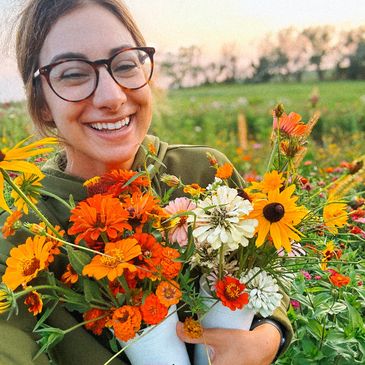 A woman holding flowers in a field of grass.