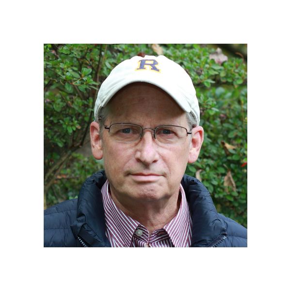 Man wearing glasses and a white cap outdoors.