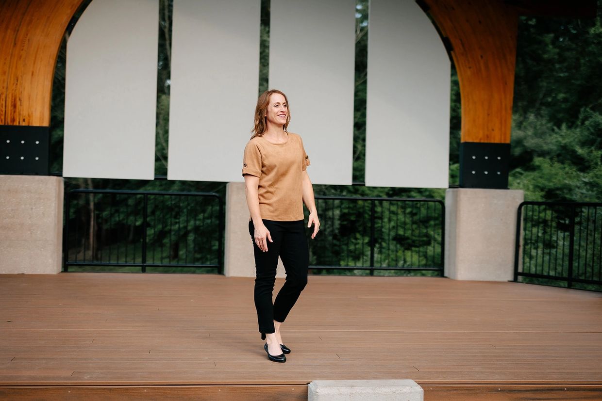 Smiling woman on the lecture stage in tan top and black pants