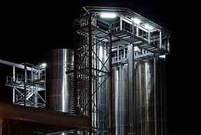 Illuminated industrial metal silos and structures at night.