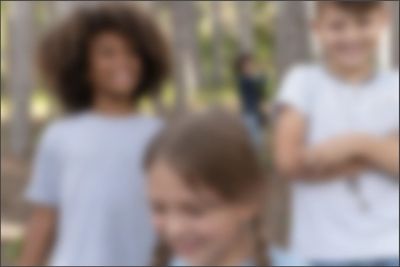 Three children outdoors, smiling and enjoying nature.