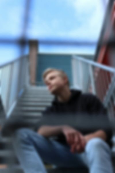 A young person sitting on outdoor stairs, blurred view.