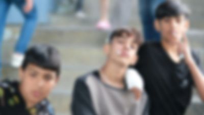 Three young boys sitting on stairs, posing for a casual photo.