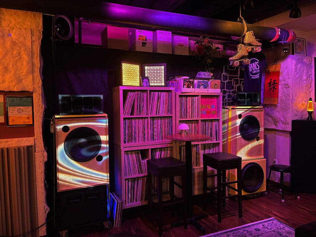 Cozy room with vinyl records, speakers, and colorful lights.