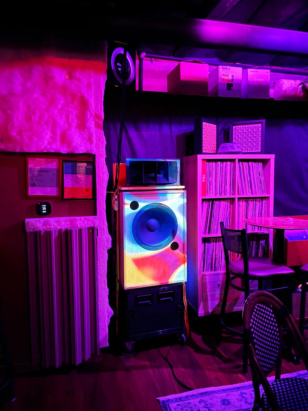 Colorful lit music room with records and speaker.
