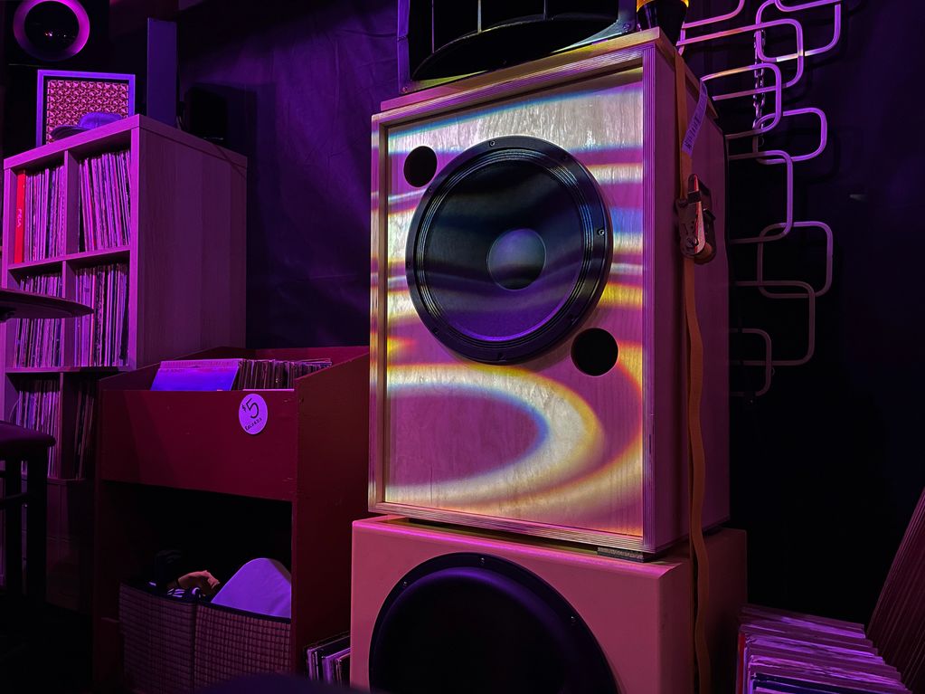 Colorful light patterns on a wooden speaker in a cozy music room.