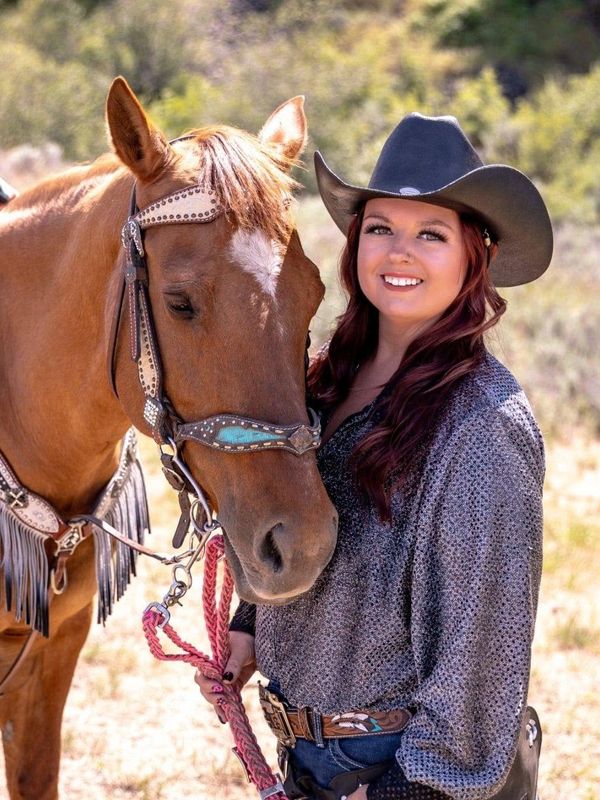 Woman in cowboy hat standing next to a horse.