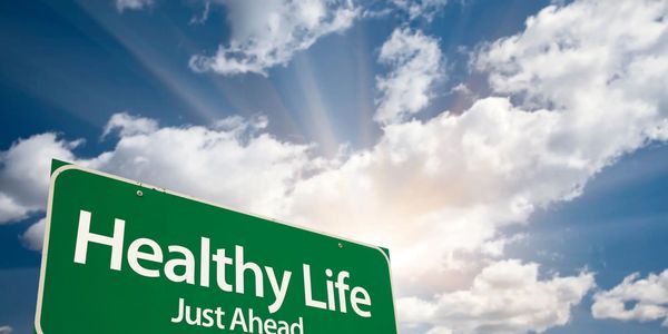 sign wordshealthy life just ahead with sunlight in clouds
