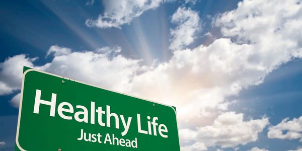 sign wordshealthy life just ahead with sunlight in clouds