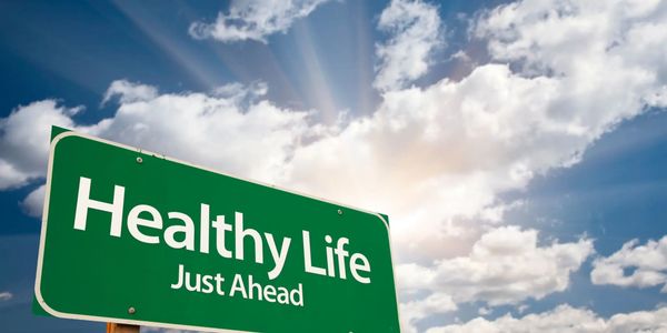 sign wordshealthy life just ahead with sunlight in clouds