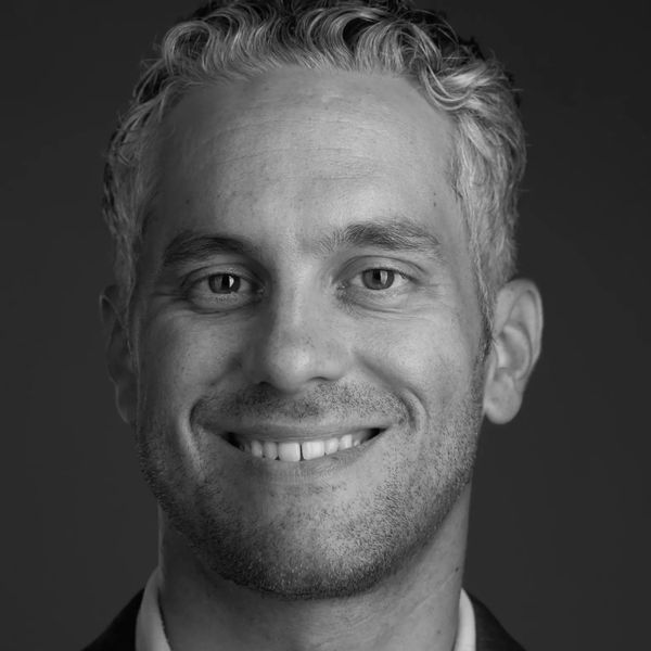 Black and white portrait of a smiling man with curly hair.