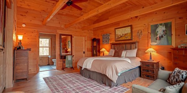 Cozy wooden cabin bedroom with a large bed and warm lighting.